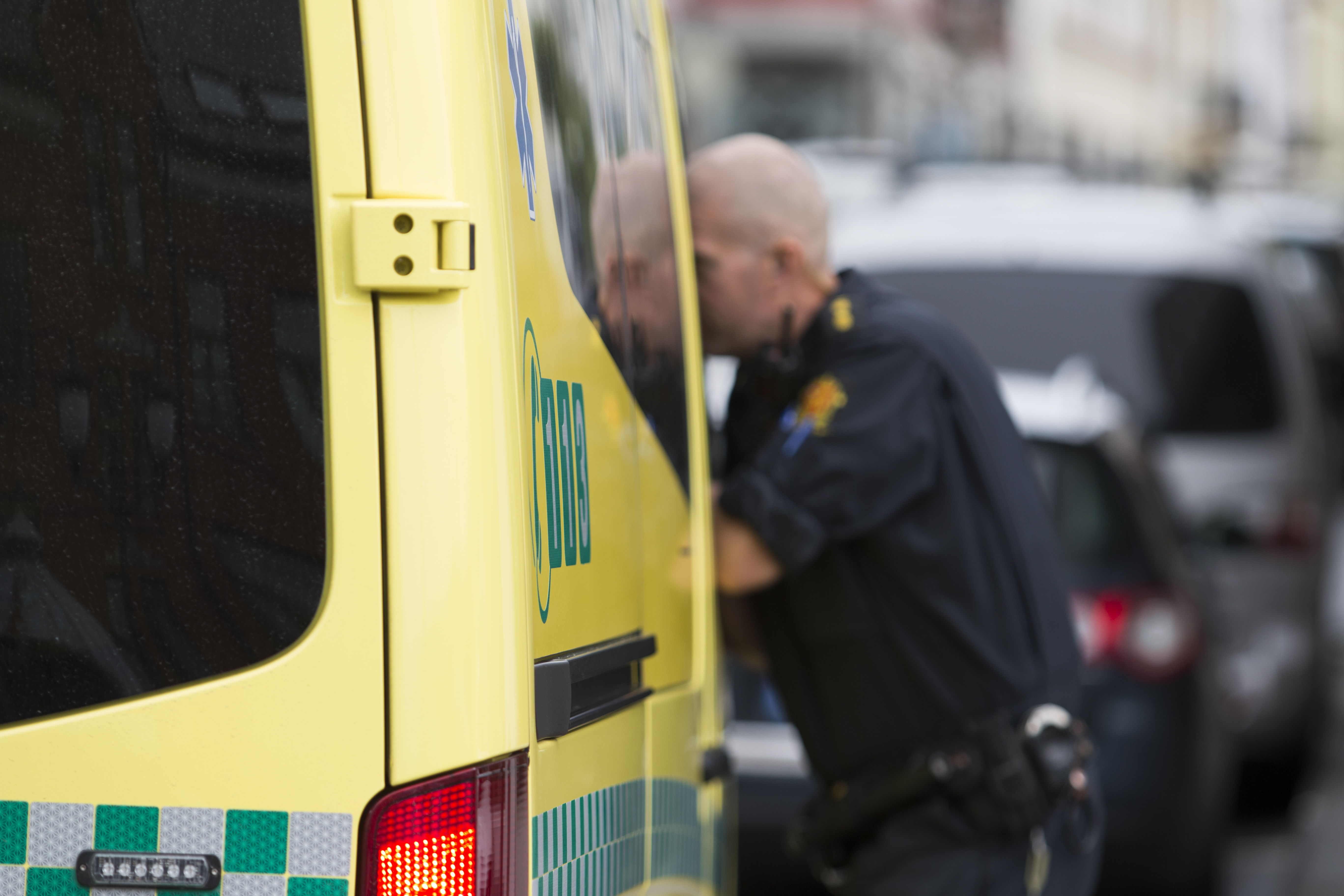 Politimann i profil lener seg inn gjennom vindu på ambulanse