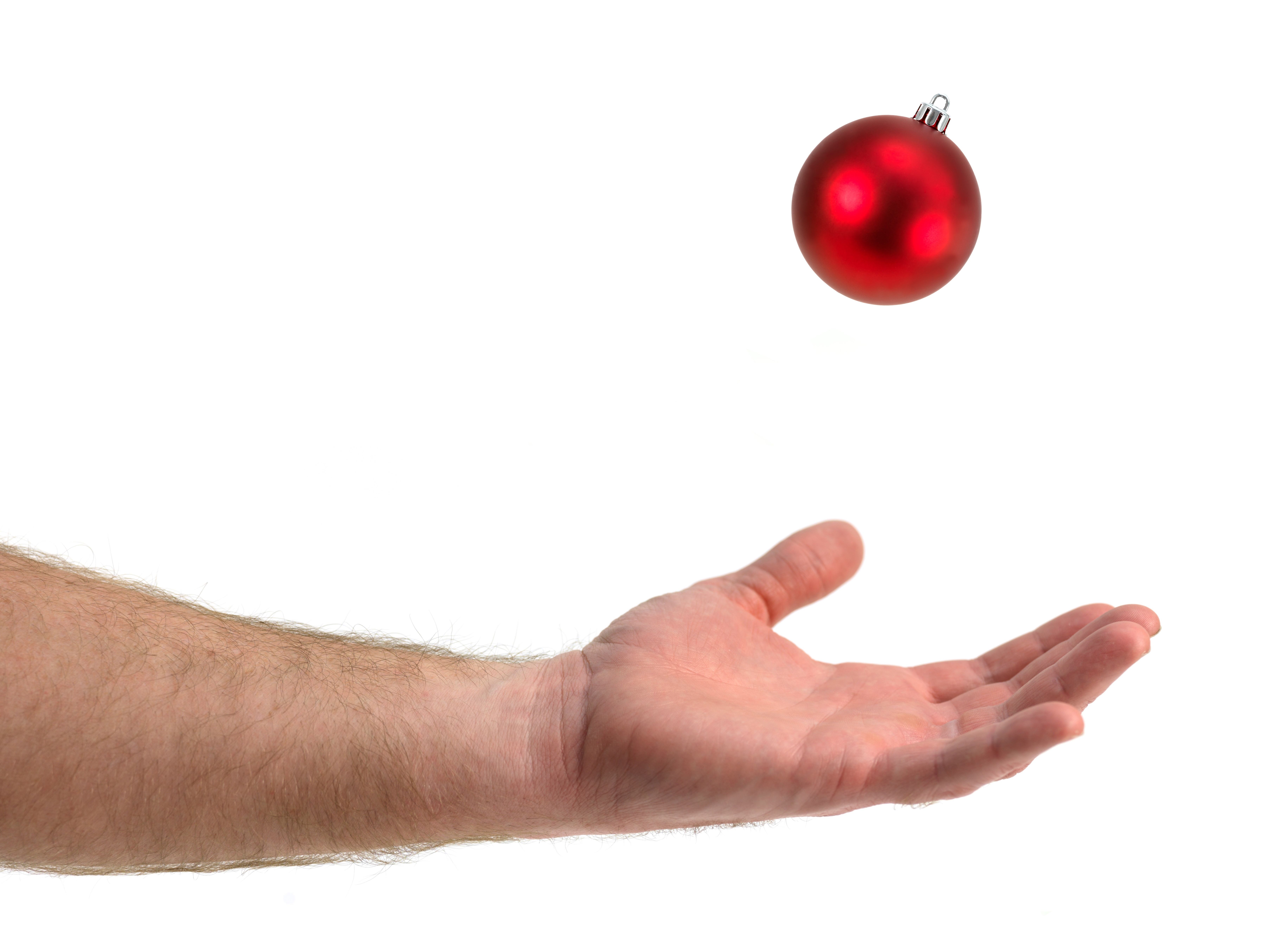 En utstrakt hånd/underarm som tar i mot en julekule